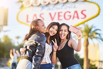 Young adults pose for a selfie in front of the Welcome to Las Vegas sign