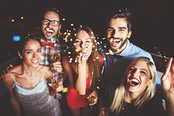 A group of friends laugh and throw confetti and a nighttime party